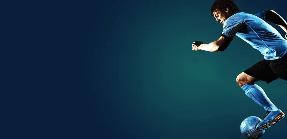 Footballer striking a ball against a dark background